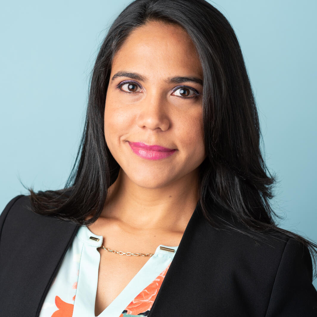 Smiling headshot of a Hispanic woman on a blue background