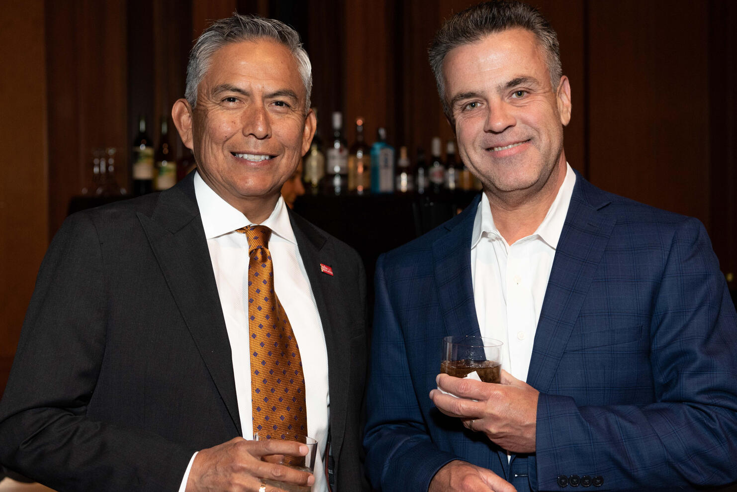Two men smiling holding drinks at a corporate party