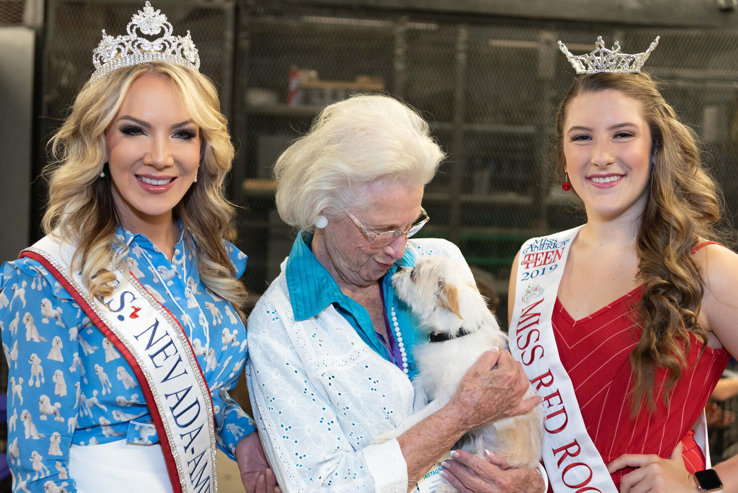 Elderly woman holding a small dog with Mrs Nevada and Miss Teen America