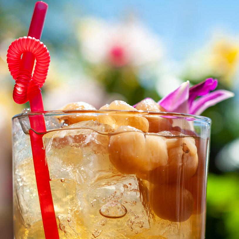 Cocktail glass filled with ice with a red straw and flower