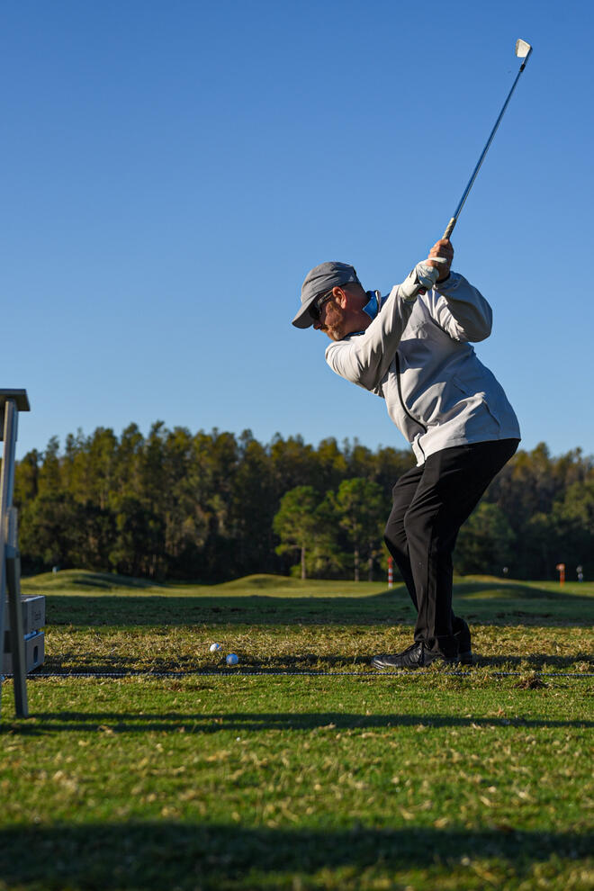 Golfer swinging a golf club on practice range